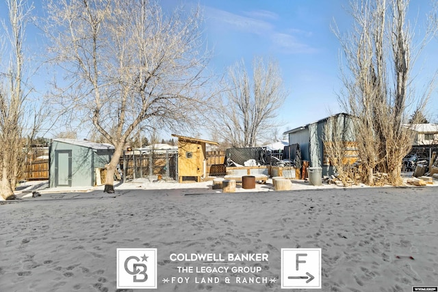 snowy yard featuring a storage unit