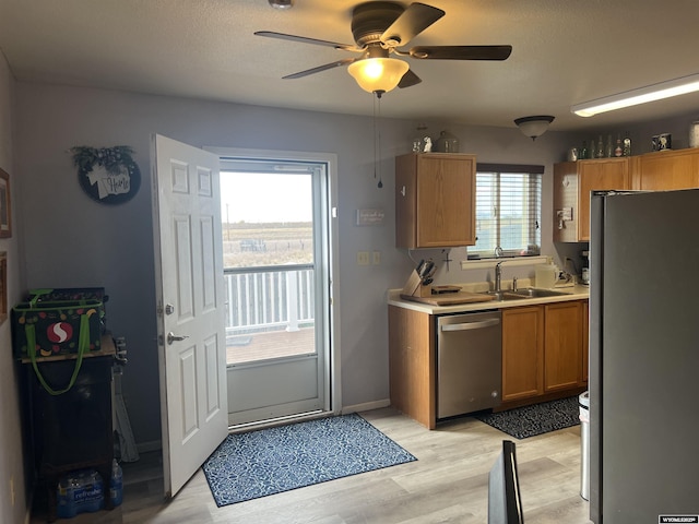 kitchen featuring sink, light wood-type flooring, ceiling fan, stainless steel appliances, and a textured ceiling