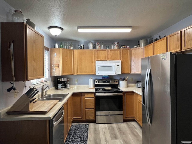 kitchen with sink, light hardwood / wood-style flooring, a textured ceiling, and appliances with stainless steel finishes