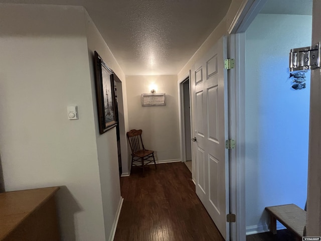 corridor with dark hardwood / wood-style floors and a textured ceiling