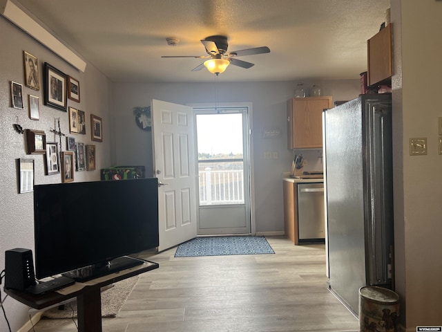 kitchen with ceiling fan, stainless steel appliances, light hardwood / wood-style flooring, and a textured ceiling