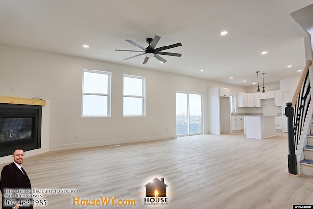 living room with a glass covered fireplace, stairway, light wood finished floors, and recessed lighting