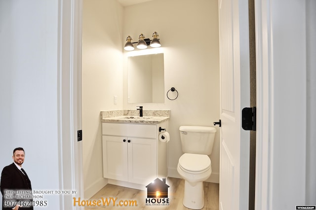 bathroom featuring toilet, baseboards, wood finished floors, and vanity