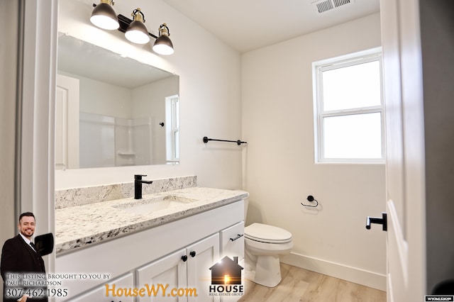 bathroom featuring toilet, wood finished floors, vanity, visible vents, and baseboards