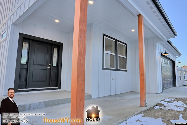 snow covered property entrance featuring board and batten siding