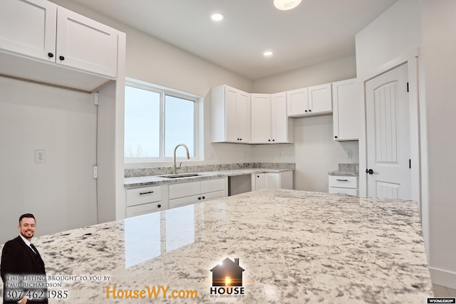 kitchen with recessed lighting, a sink, light stone countertops, and white cabinets