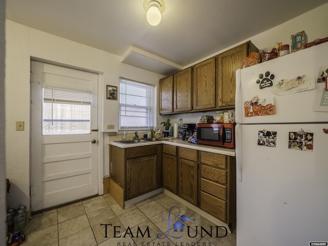 kitchen with sink, white fridge, and light tile patterned floors