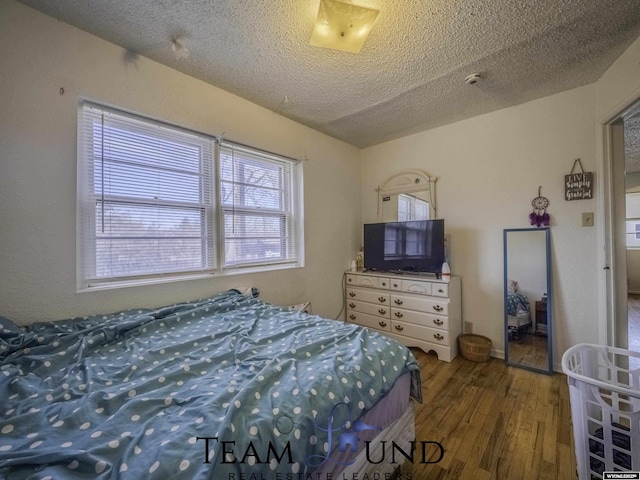 bedroom with hardwood / wood-style floors and a textured ceiling