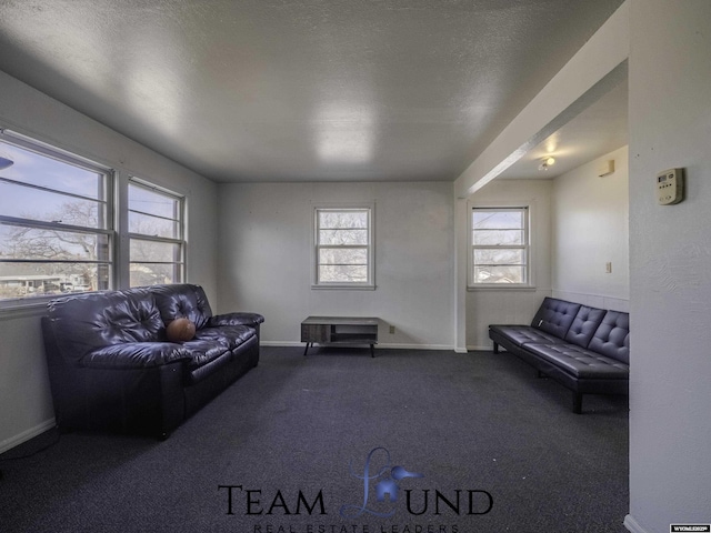 living room featuring dark carpet, a textured ceiling, and a wealth of natural light