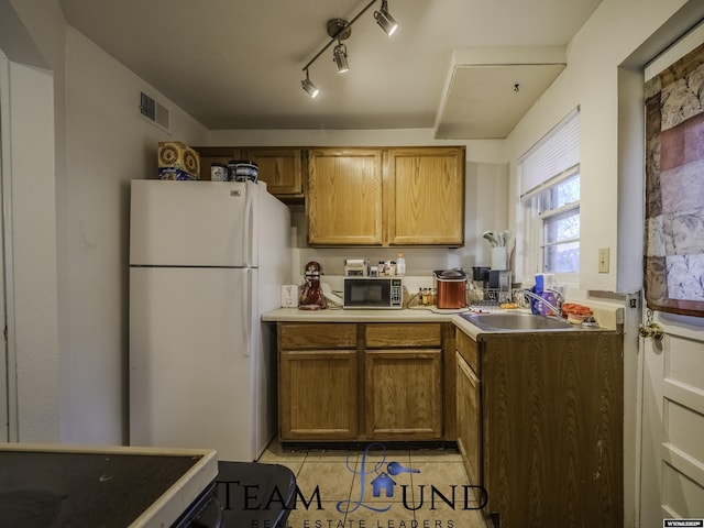 kitchen with sink, white fridge, and light tile patterned floors