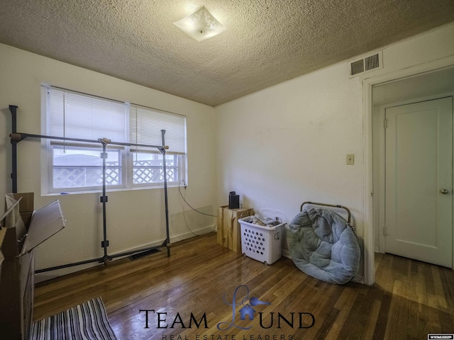 misc room with dark wood-type flooring and a textured ceiling