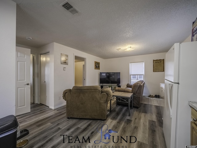 living room featuring dark wood-type flooring and a textured ceiling