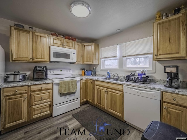 kitchen featuring sink, white appliances, light stone countertops, and hardwood / wood-style flooring