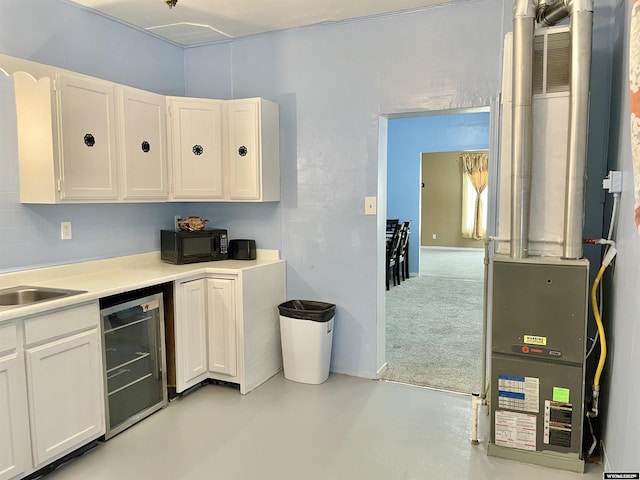 kitchen with white cabinetry, sink, heating unit, and wine cooler