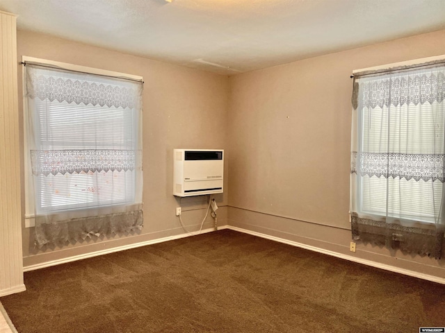 unfurnished room featuring heating unit, a wealth of natural light, and dark colored carpet