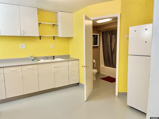 kitchen featuring white cabinetry, sink, and white fridge