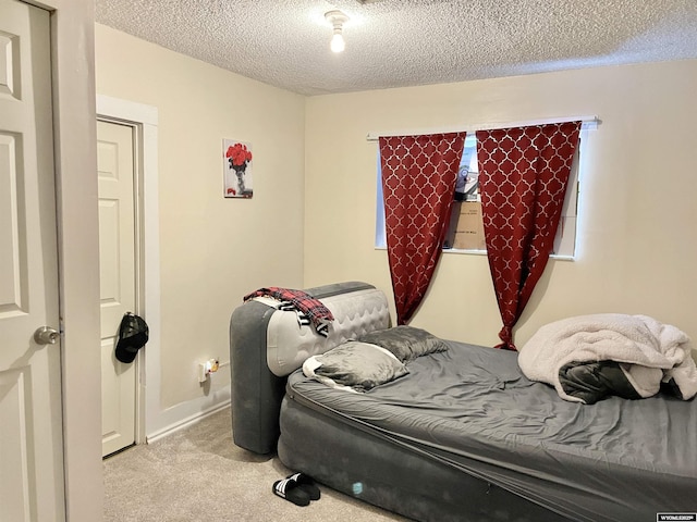 bedroom with light colored carpet and a textured ceiling