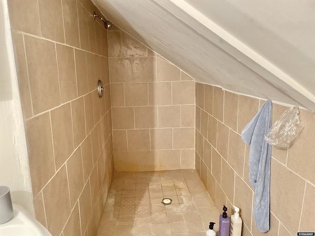 bathroom with lofted ceiling and a tile shower