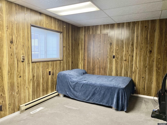 bedroom featuring a baseboard radiator, wooden walls, a paneled ceiling, and carpet floors