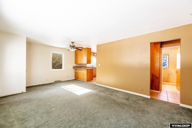 unfurnished living room with light colored carpet and ceiling fan