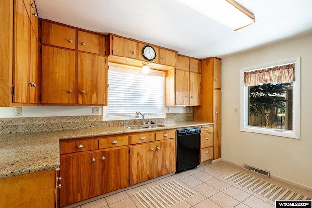 kitchen with sink, light tile patterned floors, light stone countertops, and black dishwasher