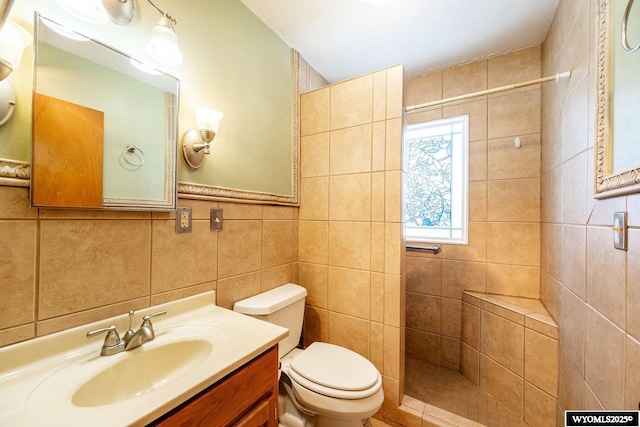 bathroom featuring vanity, toilet, tile walls, and tiled shower