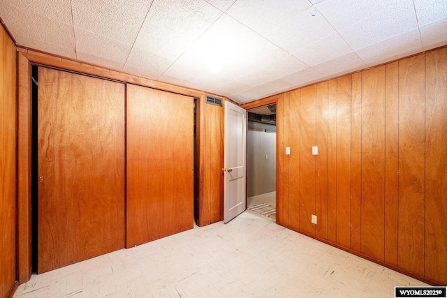 unfurnished bedroom with a closet and wood walls