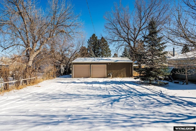 snowy yard featuring an outbuilding and a garage