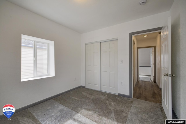 unfurnished bedroom with dark carpet and a closet