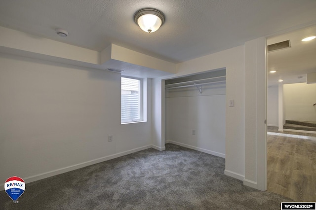 unfurnished bedroom with a closet, dark carpet, and a textured ceiling