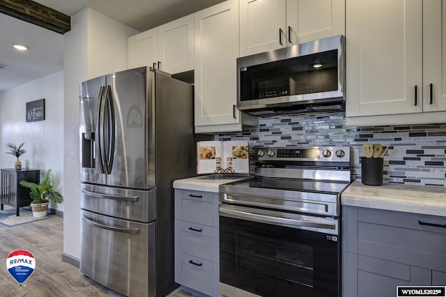 kitchen featuring white cabinetry, stainless steel appliances, light hardwood / wood-style floors, and backsplash