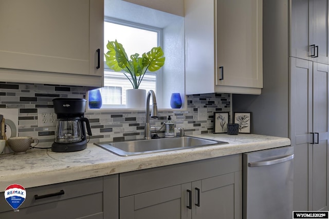 kitchen featuring stainless steel dishwasher, light stone countertops, sink, and backsplash