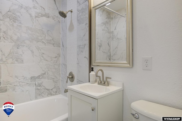 full bathroom featuring vanity, tiled shower / bath, and toilet