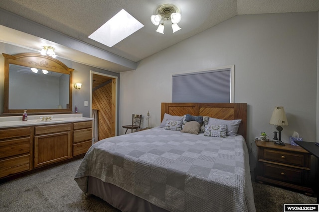 bedroom featuring vaulted ceiling with skylight, carpet flooring, a sink, and a textured ceiling