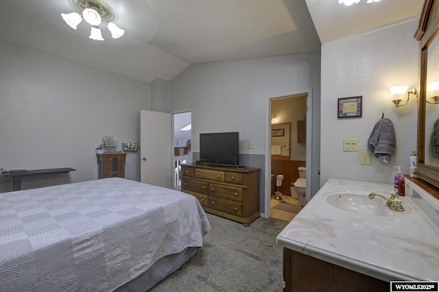 carpeted bedroom with vaulted ceiling, a sink, and ensuite bathroom