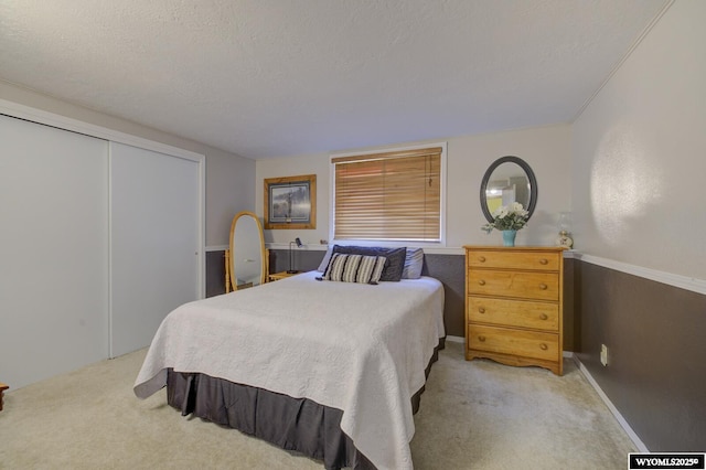 carpeted bedroom with a textured ceiling and a closet