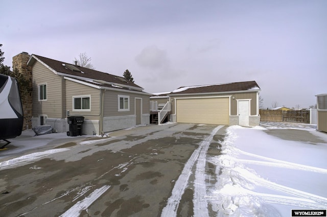 view of front of house featuring a chimney, a detached garage, fence, and an outdoor structure