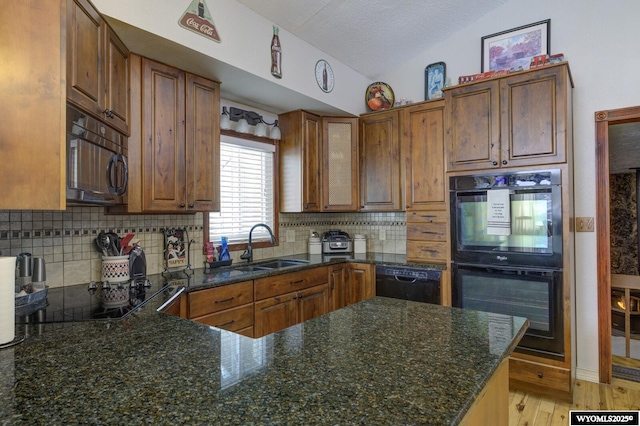 kitchen featuring light wood-style floors, brown cabinets, vaulted ceiling, black appliances, and backsplash