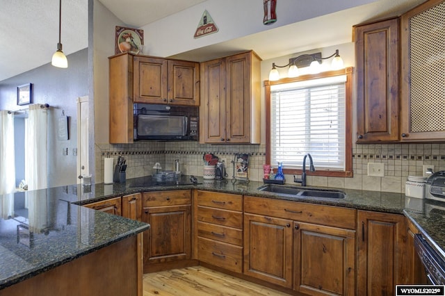 kitchen featuring light wood-style flooring, a sink, decorative backsplash, black appliances, and brown cabinetry