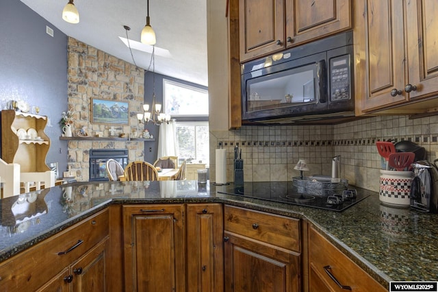 kitchen with decorative backsplash, brown cabinetry, a stone fireplace, and black appliances