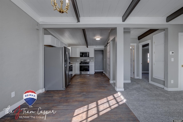 kitchen featuring appliances with stainless steel finishes, beamed ceiling, white cabinets, a barn door, and an inviting chandelier