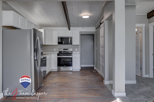 kitchen featuring beamed ceiling, stainless steel appliances, a barn door, and white cabinets