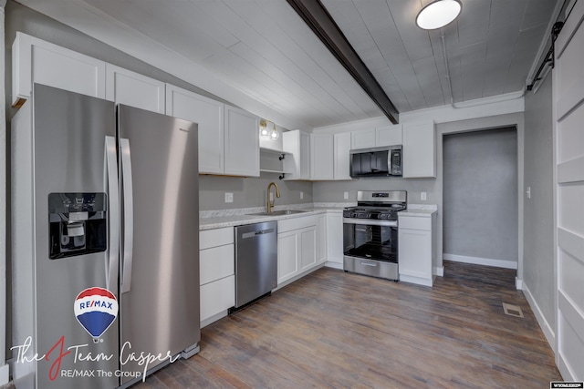 kitchen with appliances with stainless steel finishes, beamed ceiling, white cabinetry, sink, and dark wood-type flooring