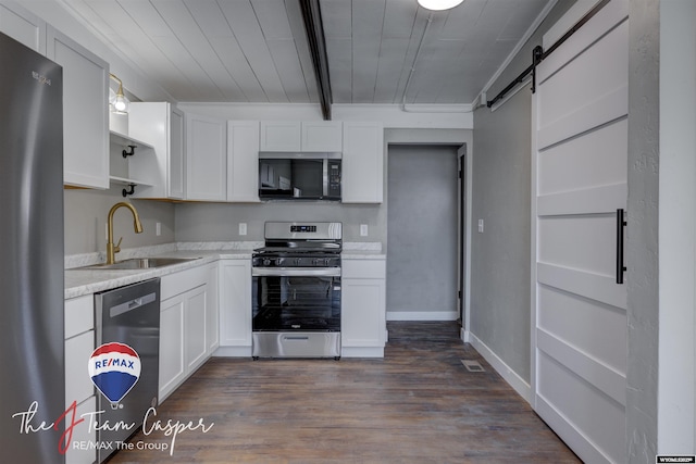 kitchen featuring sink, appliances with stainless steel finishes, dark hardwood / wood-style flooring, a barn door, and white cabinets