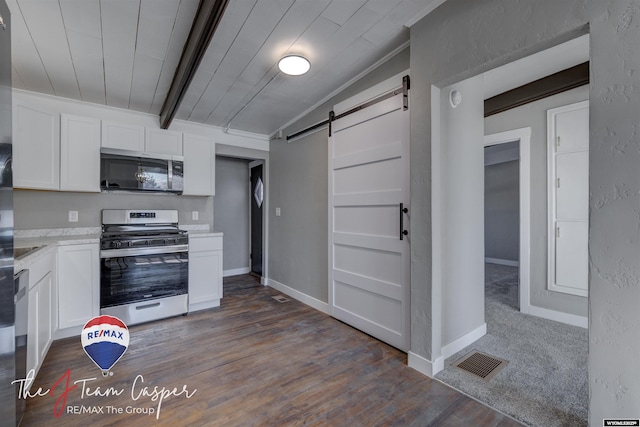 kitchen with appliances with stainless steel finishes, white cabinets, dark hardwood / wood-style flooring, a barn door, and beam ceiling