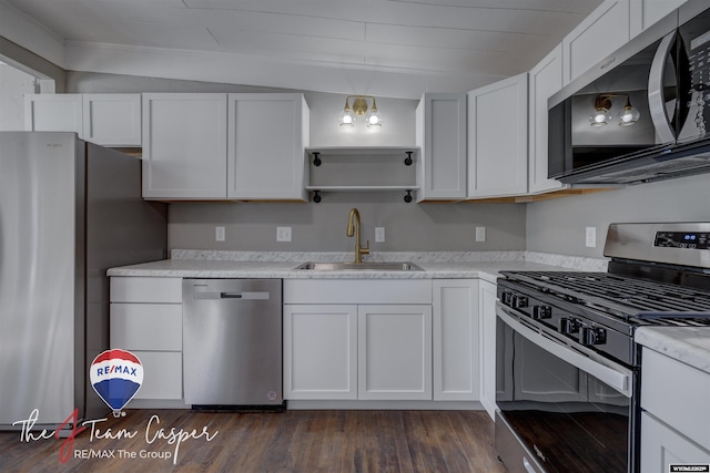 kitchen with sink, dark wood-type flooring, appliances with stainless steel finishes, light stone counters, and white cabinets