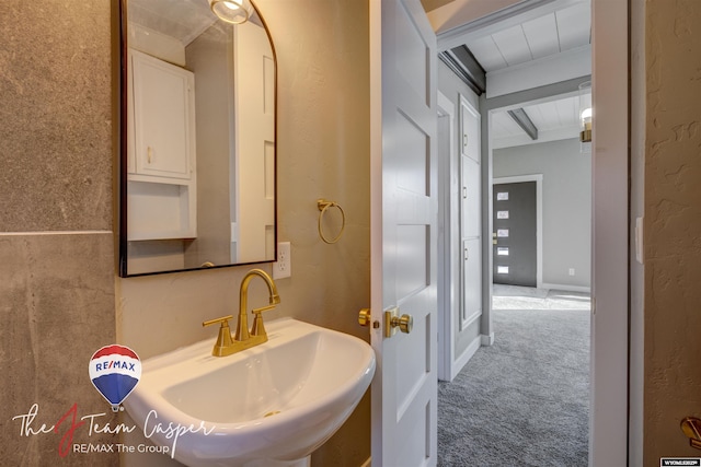 bathroom featuring beam ceiling and sink