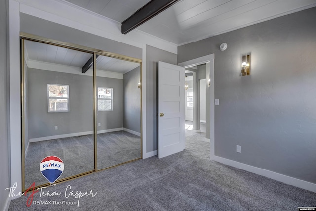 unfurnished bedroom featuring ornamental molding, carpet flooring, beam ceiling, and a closet