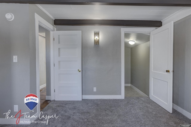 unfurnished bedroom with carpet flooring and beam ceiling