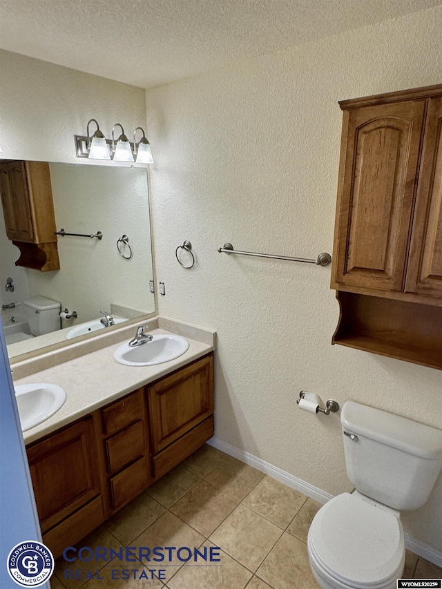 bathroom with tile patterned flooring, vanity, a textured ceiling, and toilet